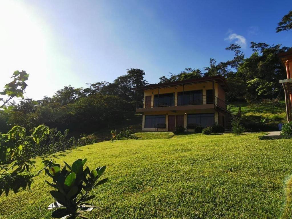 Two-story building with flat roof, big windows, lawn and trees
